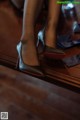 A close up of a woman's shoes on a wooden floor.