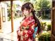 A woman in a red kimono standing in front of a building.