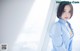 A woman in a blue shirt leaning against a window.