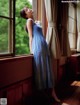 A woman in a blue dress looking out a window.