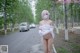 A woman in a white dress is walking down the street.