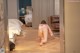 A woman in a pink dress is bending over on the floor.