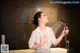 A woman in a white shirt is holding a shower head.