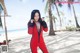 A woman in a red jumpsuit on the beach.