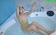 A naked woman sitting in a bathtub with water.
