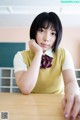 A woman sitting at a table with her hand on her chin.