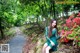 A woman in a green dress sitting on a rock in the woods.