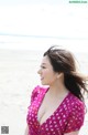 A woman in a pink dress standing on a beach.